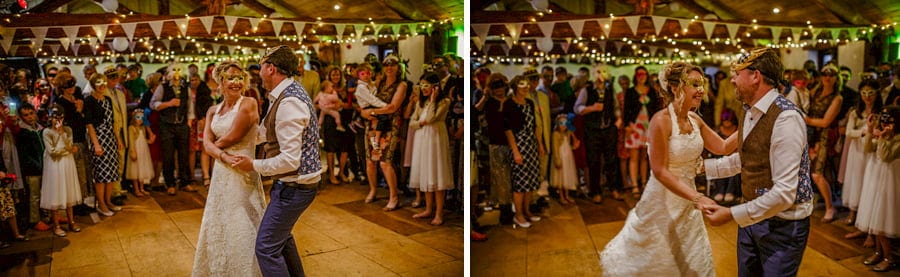 The bride and groom dance as the wedding guests stand and watch along the corner of the dancefloor