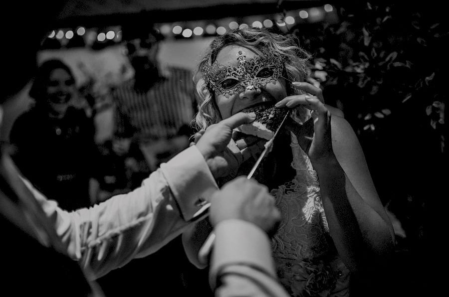 The groom places a piece of cake into the mouth of the bride