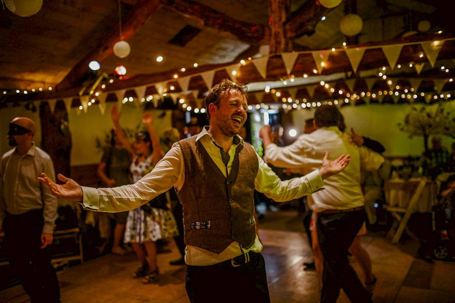 The groom opens his arms and sings during a song played by the wedding band