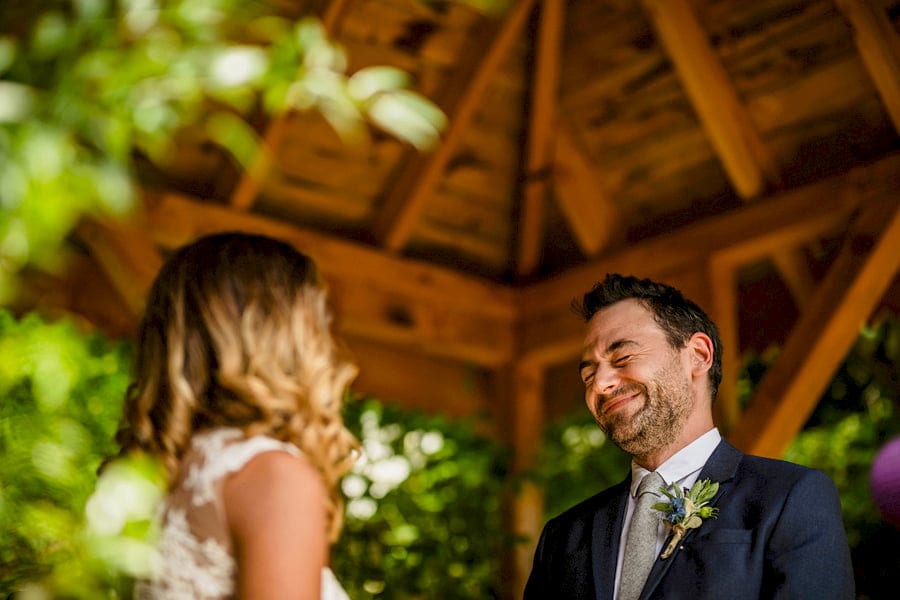 The groom laughs with the bride at the outdoor ceremony at Pennard house, Somerset