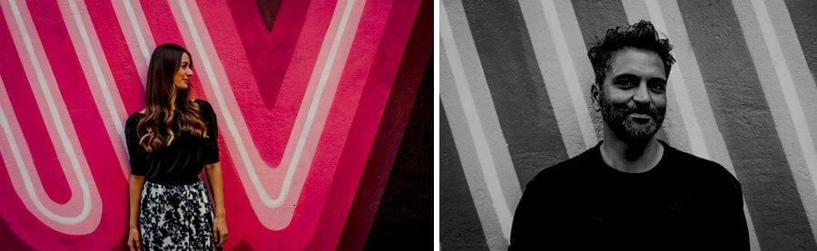 A man and lady pose for a photograph against a wall