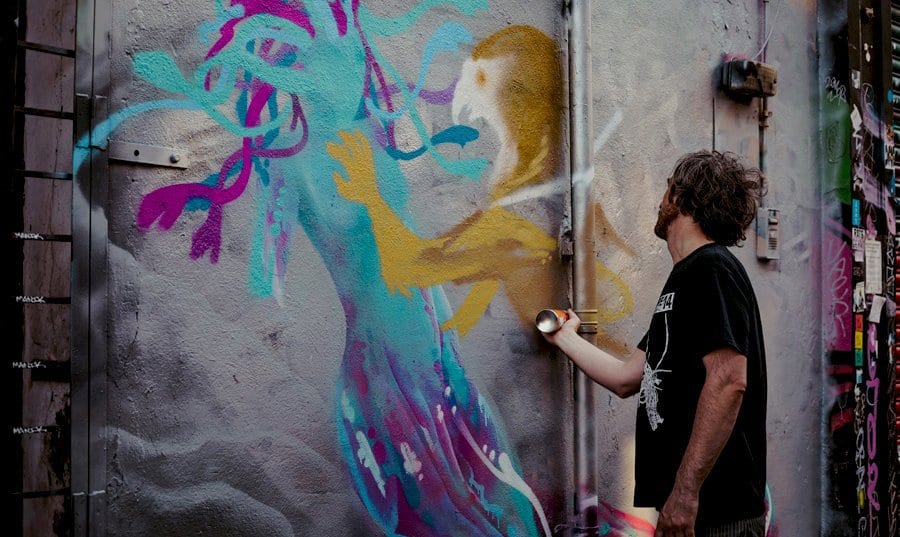 A man spray paints a wall