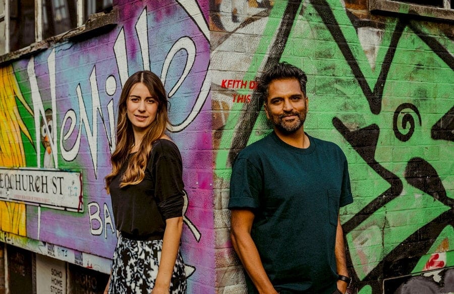 A lady and a man pose for a photograph against a wall in Shoreditch, London