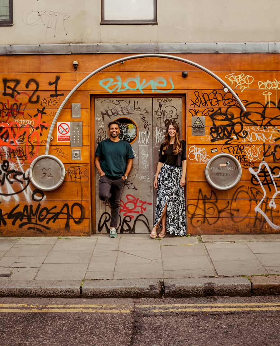 A lady and a man lean against a doorway and pose for a photograph in Shoreditch, London