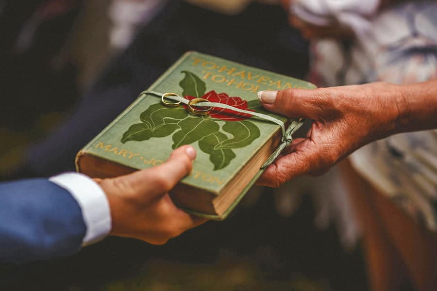 A book is passed from one guest to another with wedding rings strapped onto the front cover