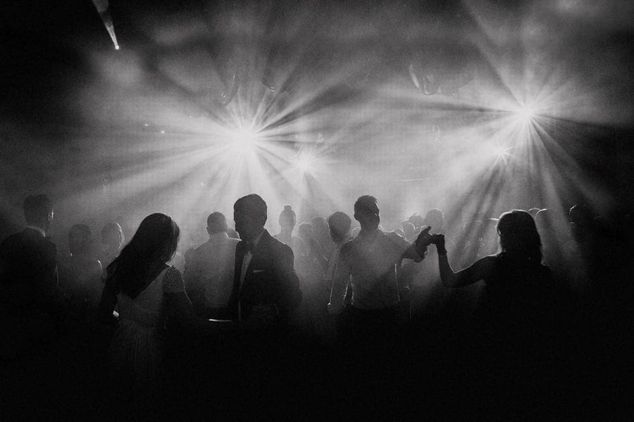 The bride and groom dance with the wedding party on the dancefloor of a big hall
