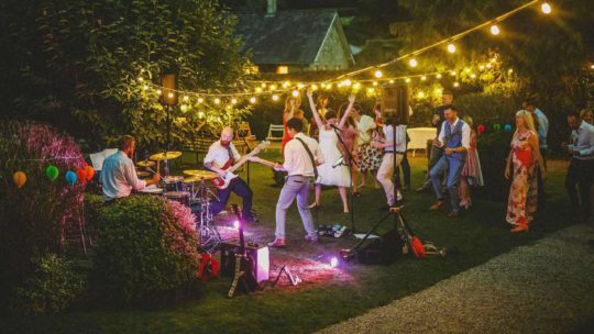 The wedding party dance on the lawn in front of the wedding band