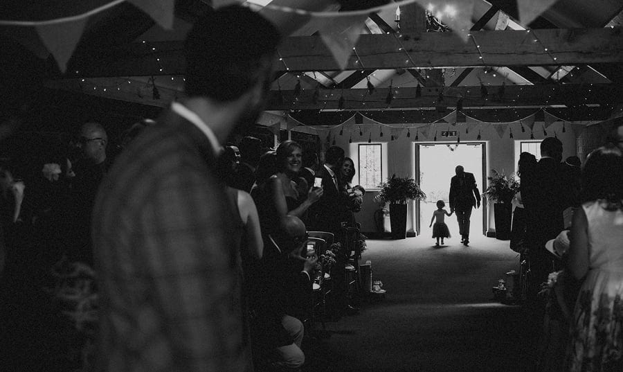 A flower girl walks towards the groom holding her grandfathers hand