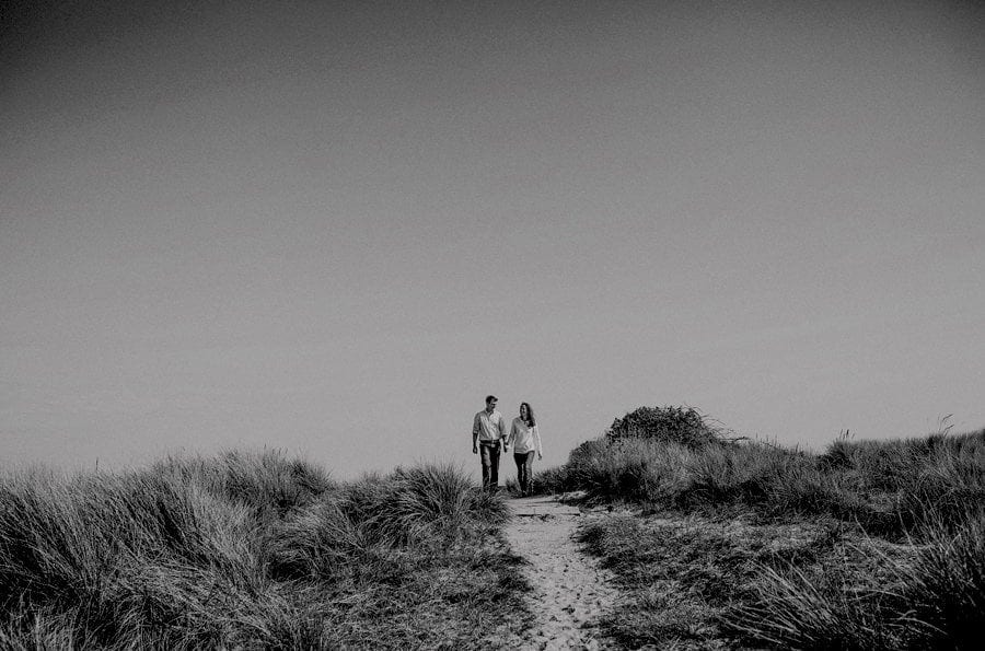 A man and lady walk hand in hand along a path