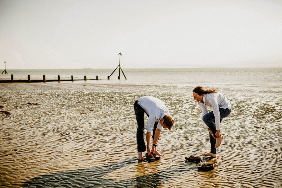 The lady and the man take off their sandals on the beach at West Wittering
