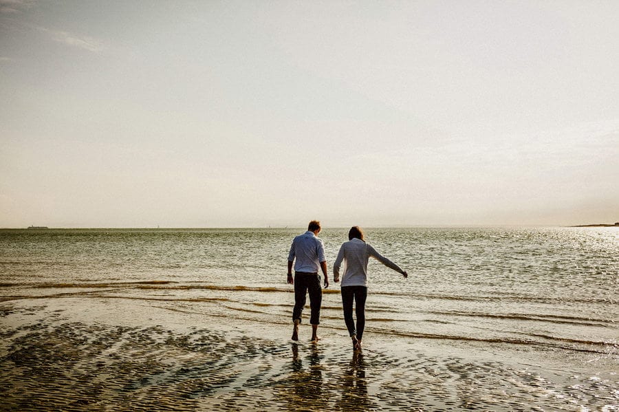The lady and the man walk together towards the sea on the beach at West Wittering
