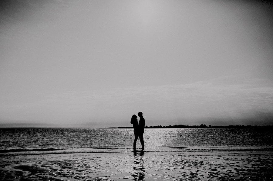 The man and the lady embrace and look at each other on the beach