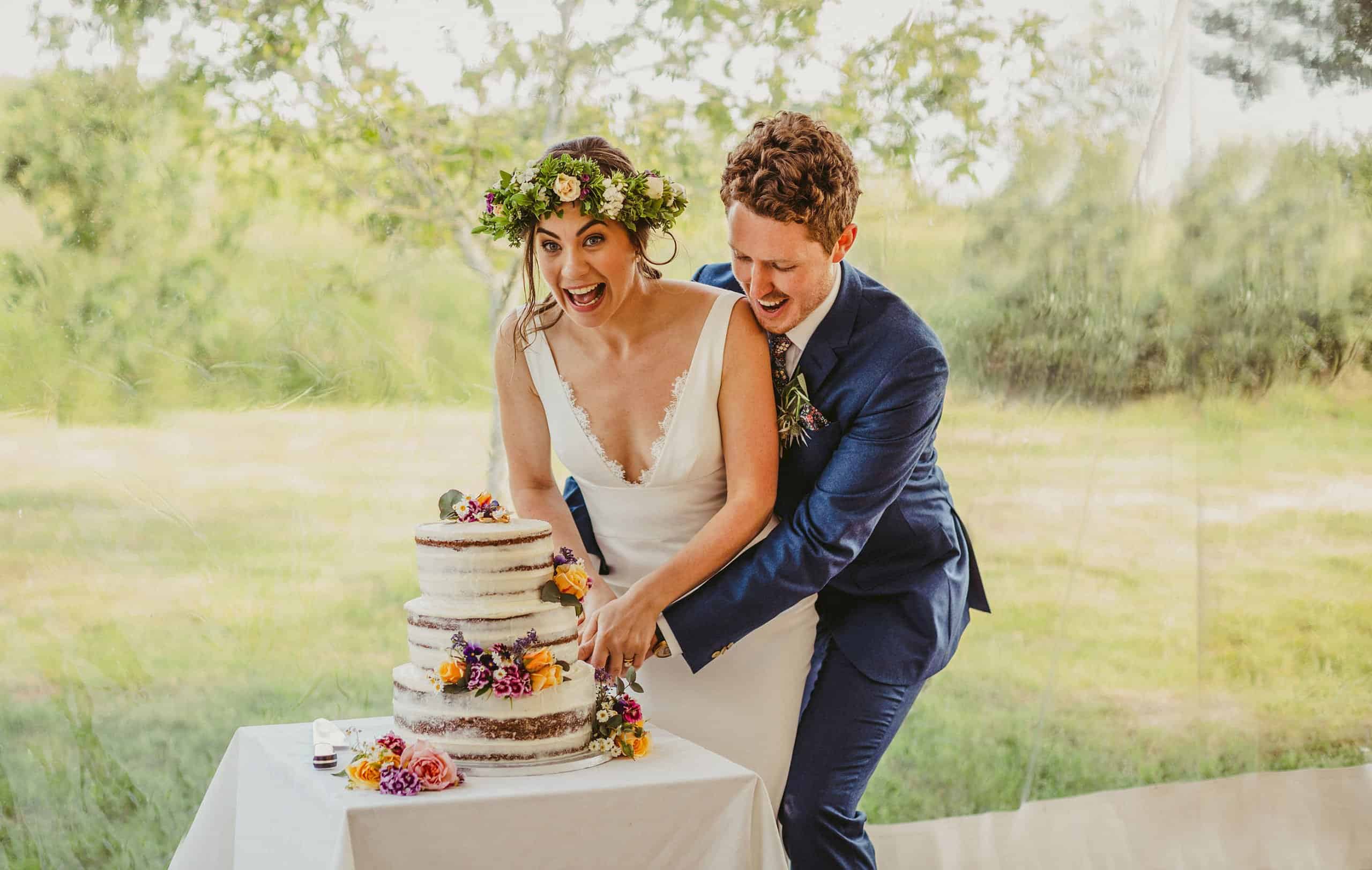 The bride and groom cut the cake together in the marquee