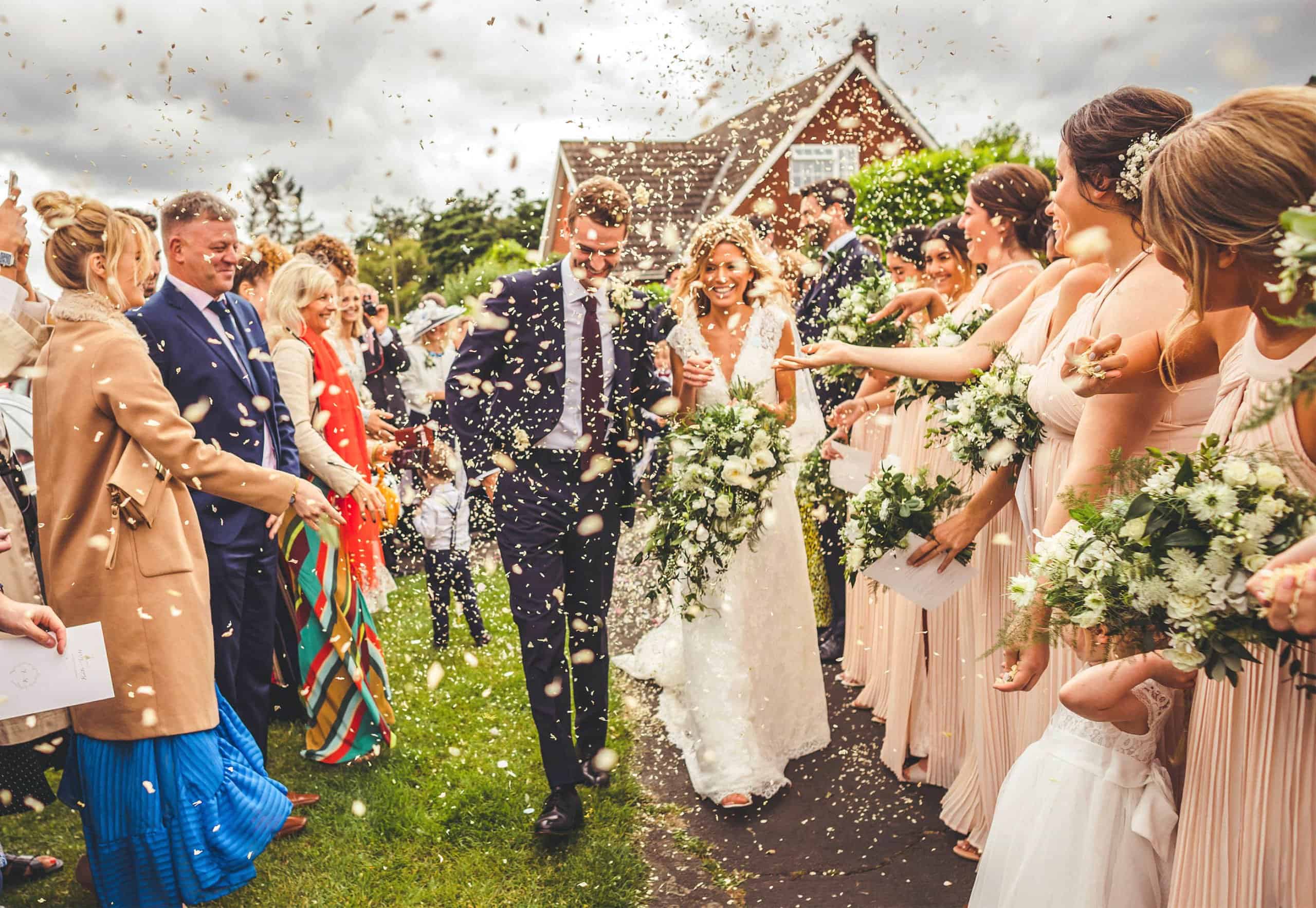 The bride and groom are showered with confetti thrown by the wedding guests