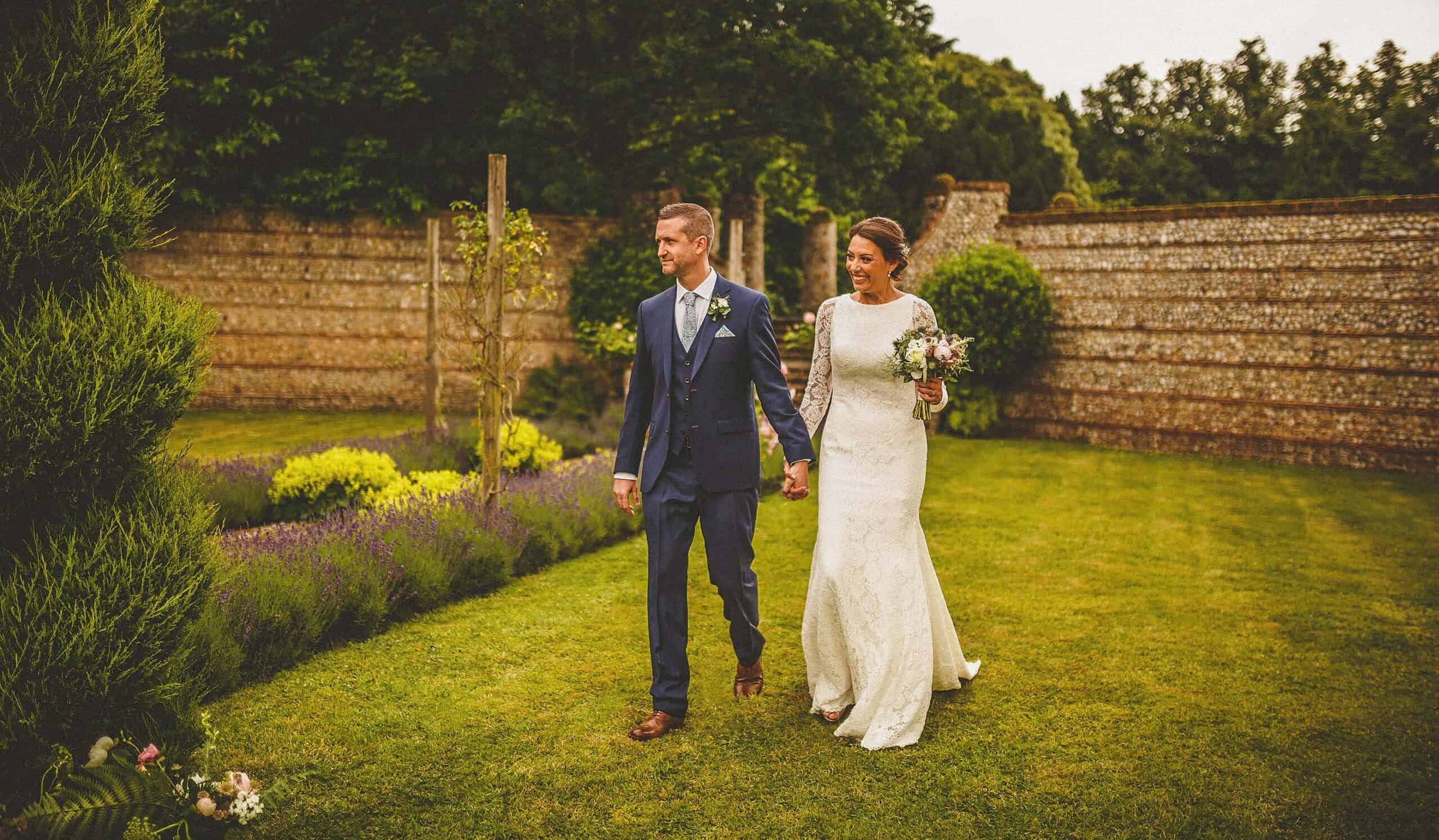 The bride and groom walk hand in hand towards the marquee at Voewood House in Norfolk