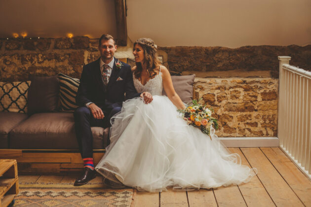 The bride and groom pose for a photograph in the Tithe Barn in Symondsbury